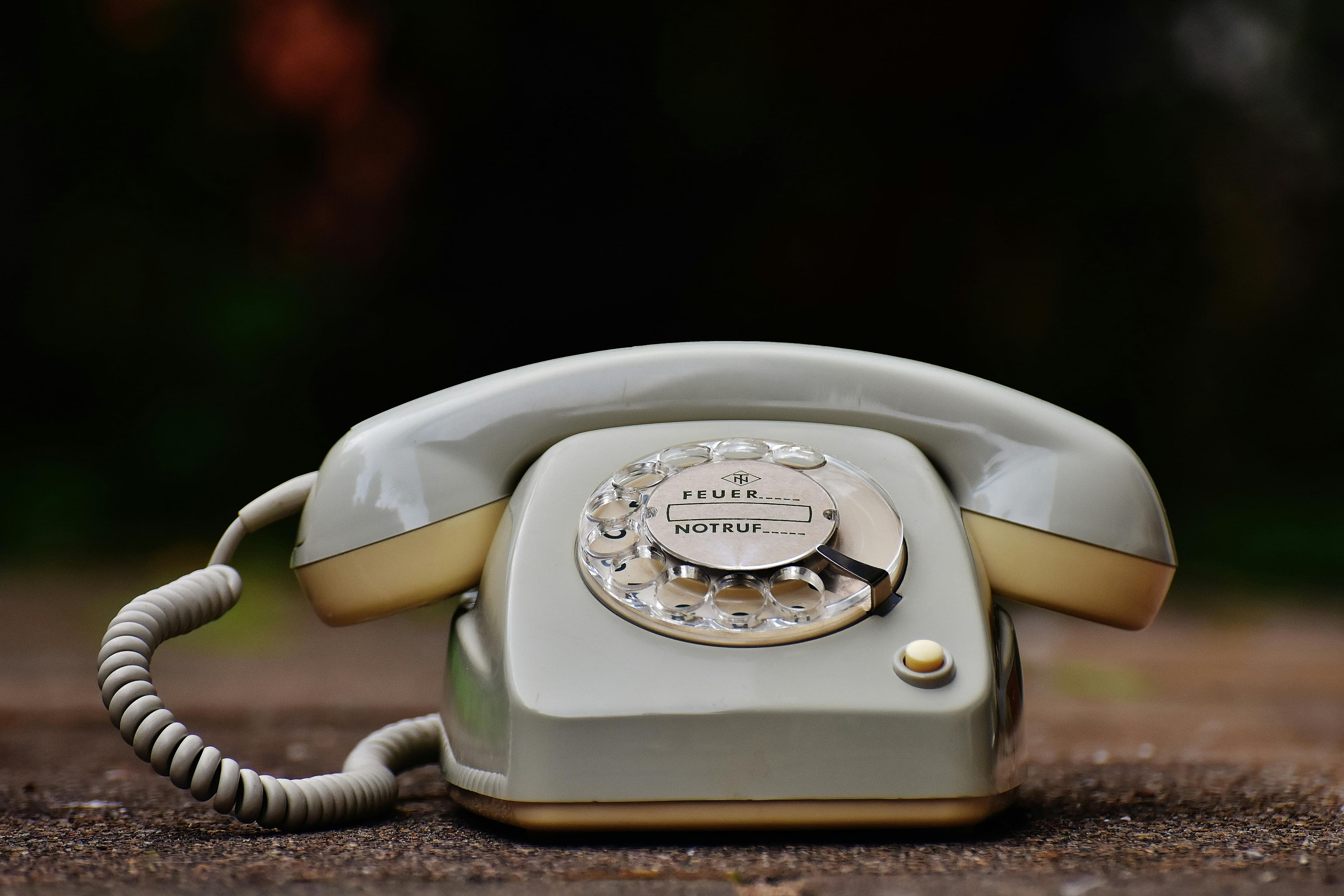 A vintage gray rotary telephone on a wooden surface, symbolizing contact and communication.